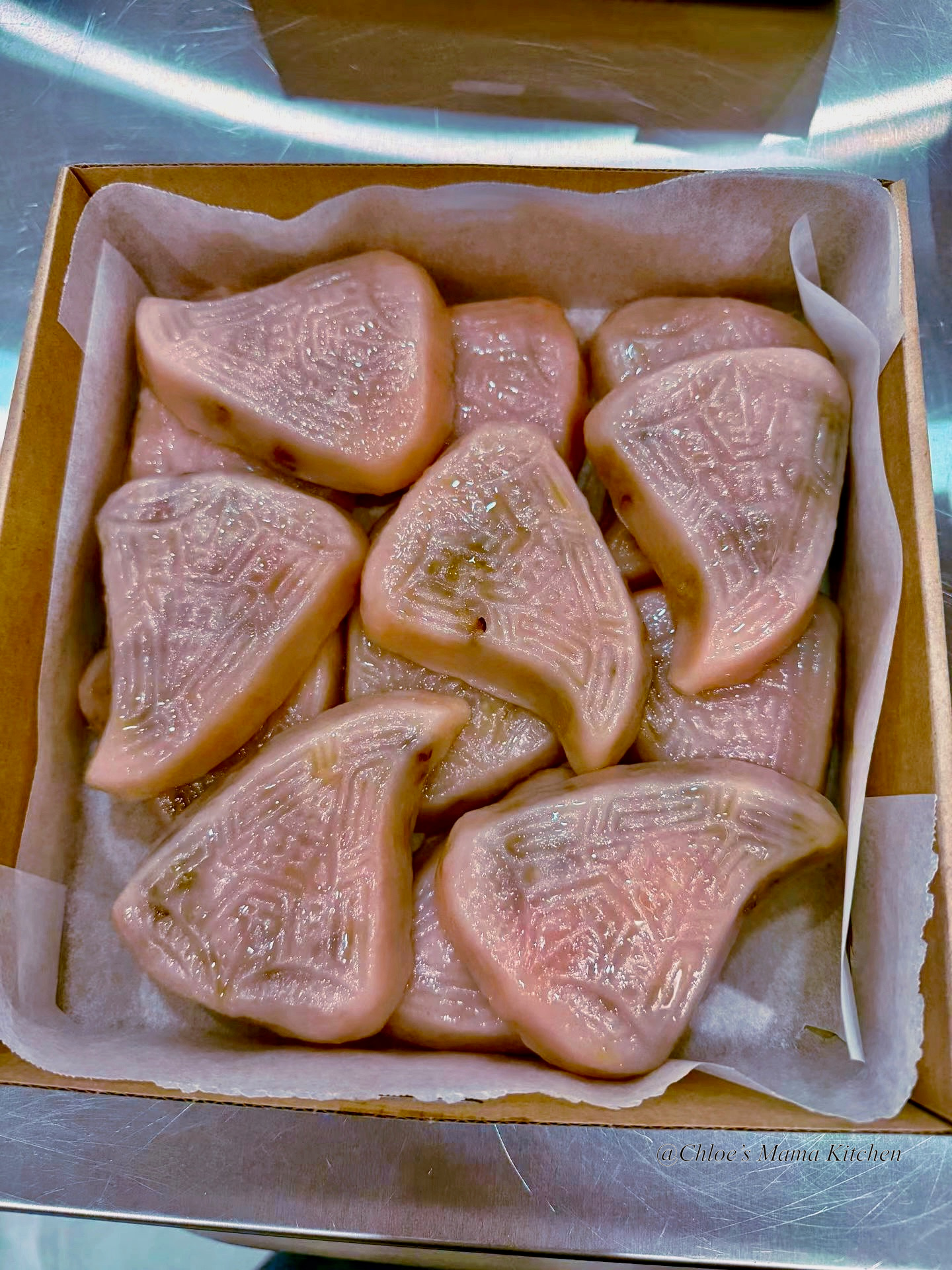 A larger paper-lined box filled with pink patterned Teochew Png Kuih