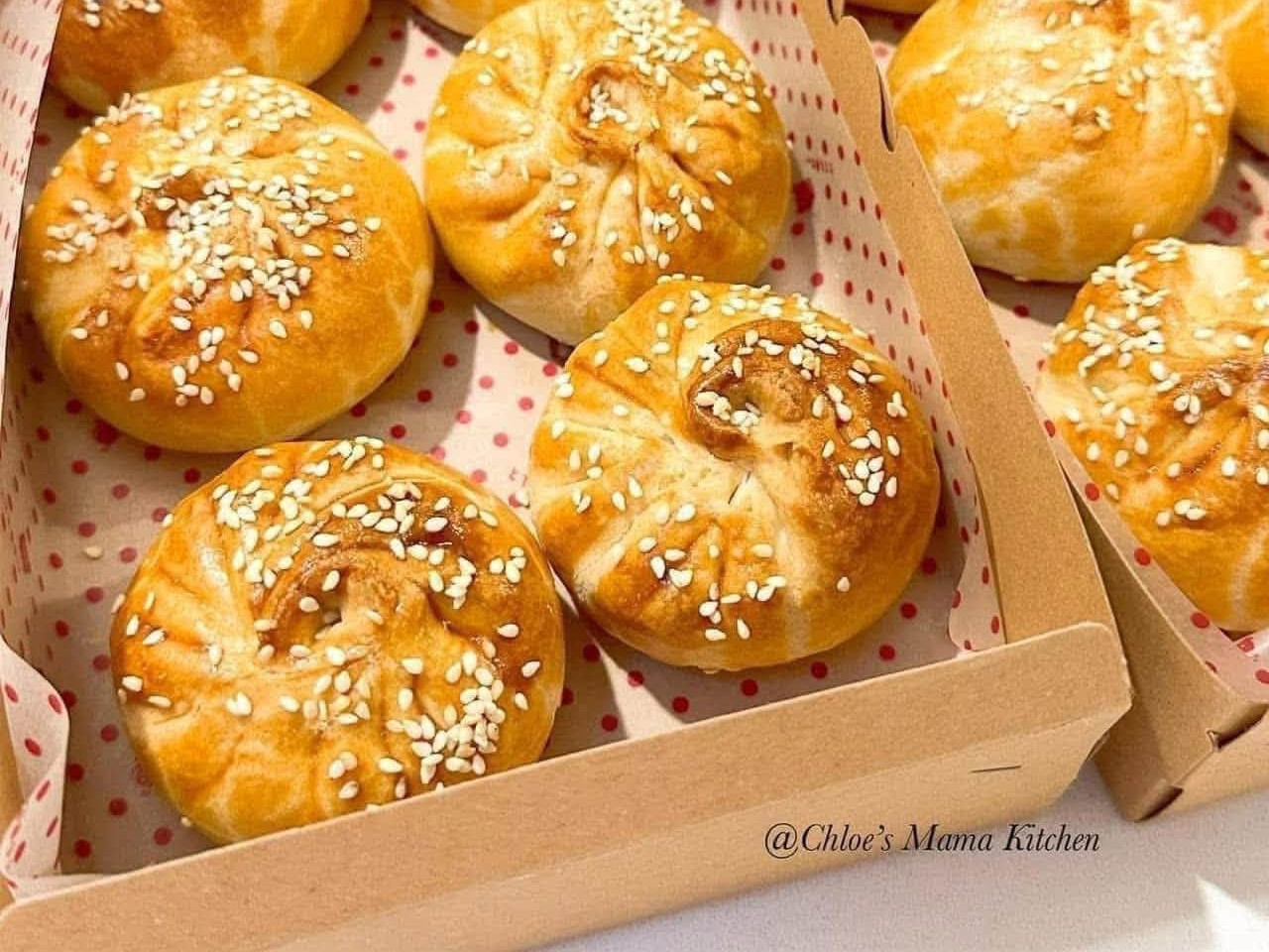 Golden baked Siew Bao with sesame, photographed in paper-lined boxes. Photograph does not establish the selling quantity.