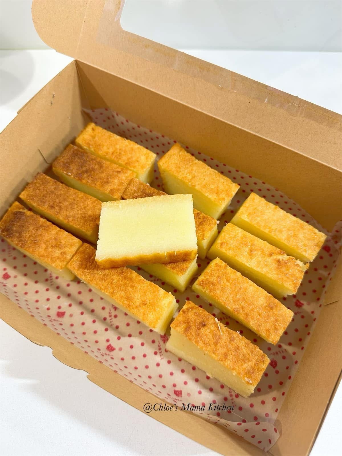 Bingka Ubi cassava cake pieces in a box, photographed by Chloe’s Mama Kitchen.
