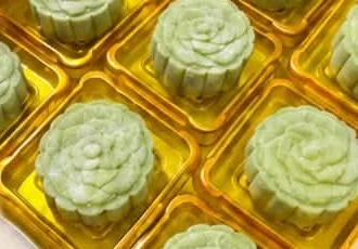 Green snow skin durian mooncakes in gold trays.