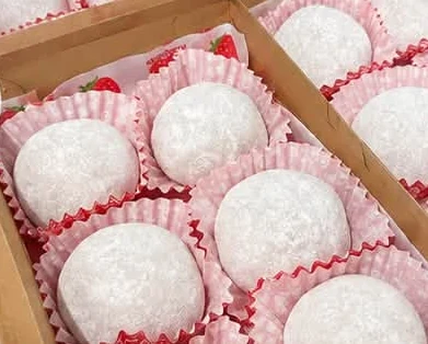 Peanut mochi in pink and white paper cases.