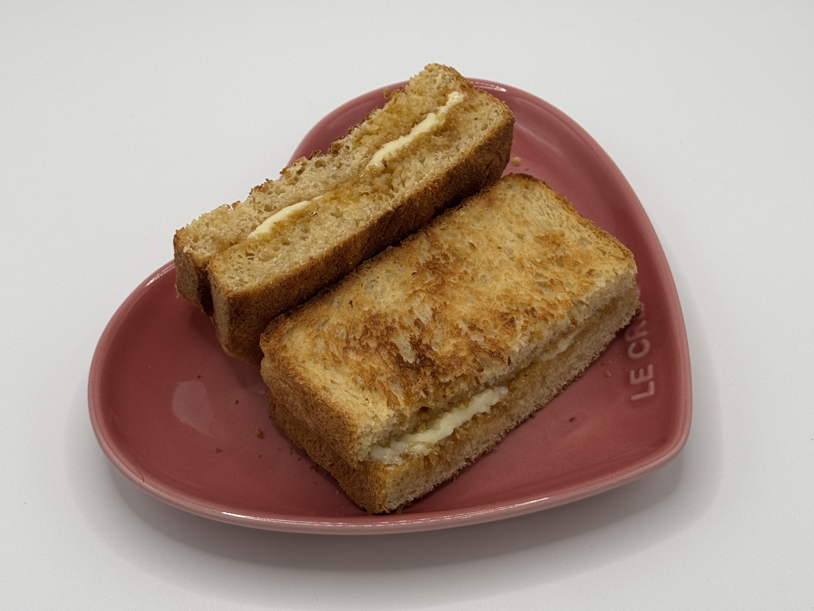 Kaya butter toast on a pink heart-shaped plate, showing the butter and kaya between slices.